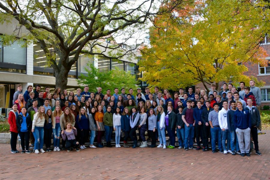 The+Class+of+2019+pose+for+a+glass+picture+in+the+fall+colors+of+Lilly+Courtyard.