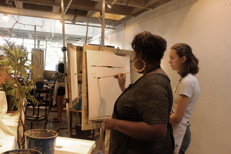 Upper School Art Teacher Mara Duvra shows a student a brushstroke.