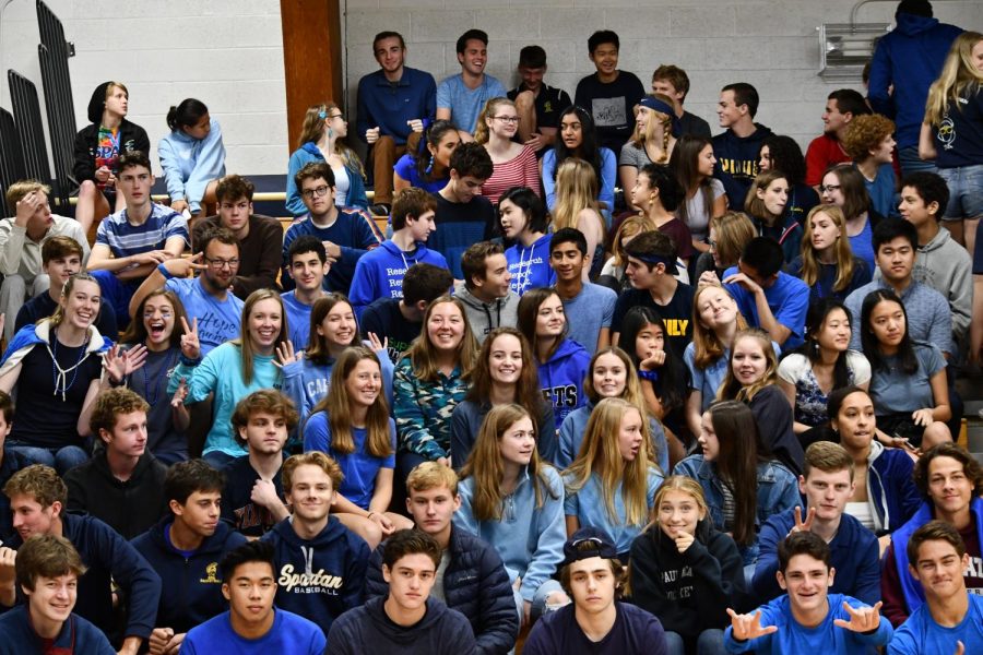 Seniors, wearing blue today, prepare for the kick off assembly, smiling.