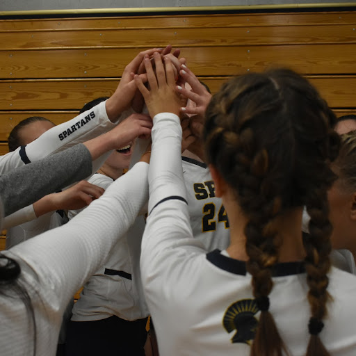 The Girls Varsity Volleyball team huddles before the start of the game. 
