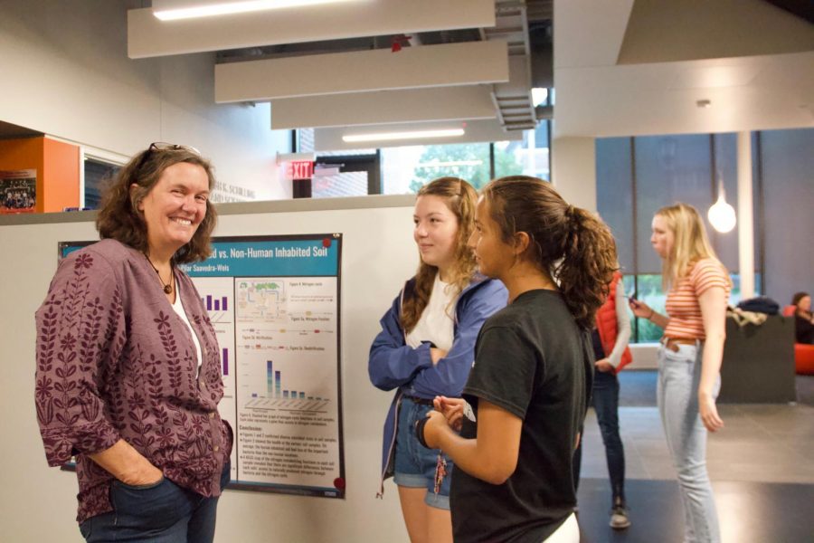 Retired science teacher Beth Seibel-Hunt listens to juniors Izzy Medrano and Pilar Saavedra-Weis findings from Costa Rica. 