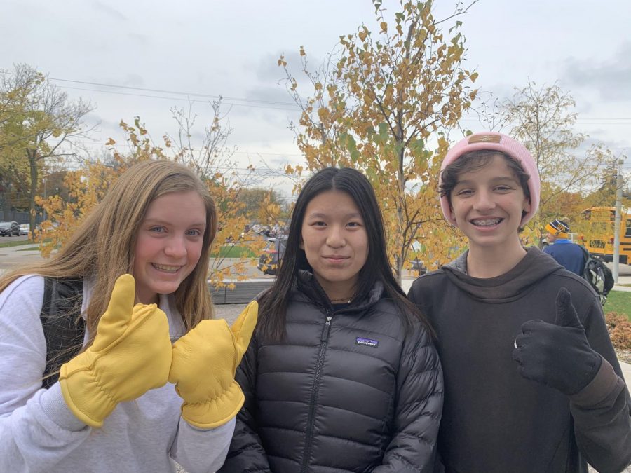 9th graders Greta Magnuson, Ivy Raya, and Aaron Lindeman stand outside of Huss Building in winter coats, hats, and gloves. 