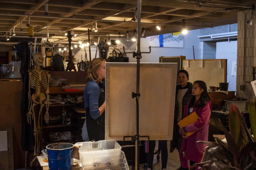 Sophomore Annika Brelsford shows a visiting family a painting that she is working on.