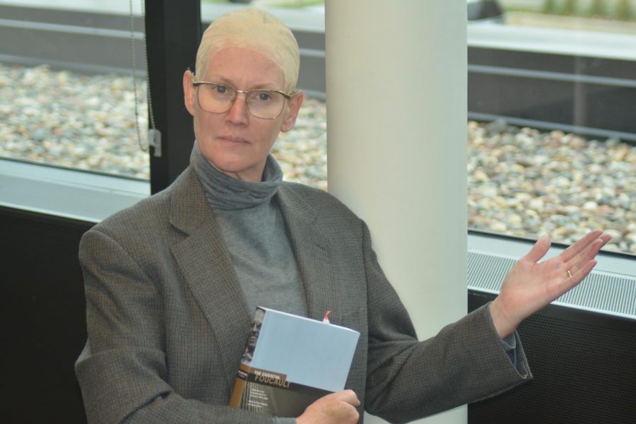 Upper school history teacher, Andrea Moerer, dressed up as famous French historian Michel Foucault. She poses for a photo carrying his book. 