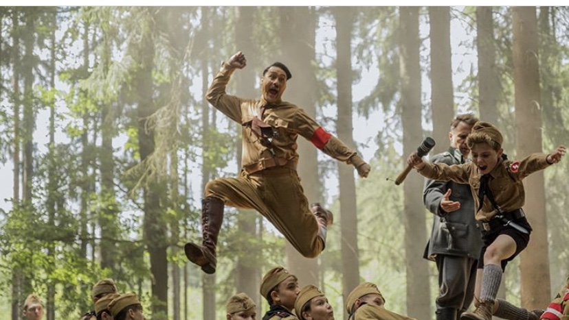 Director Taika Waititi who plays Jojo's imaginary friend jumps in the air with Jojo Rabbit (played by Roman Davis). 