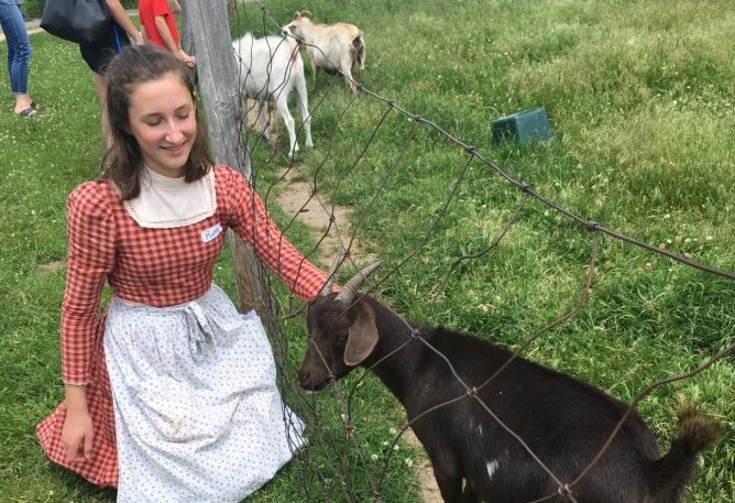  Sophomore Ruth Mellin pets a goat at Gibbs Farm in her period clothing.
