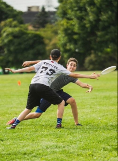 This is a photo of Levi Smetana playing ultimate in 9th grade. Here, he throws the disc around the defender.