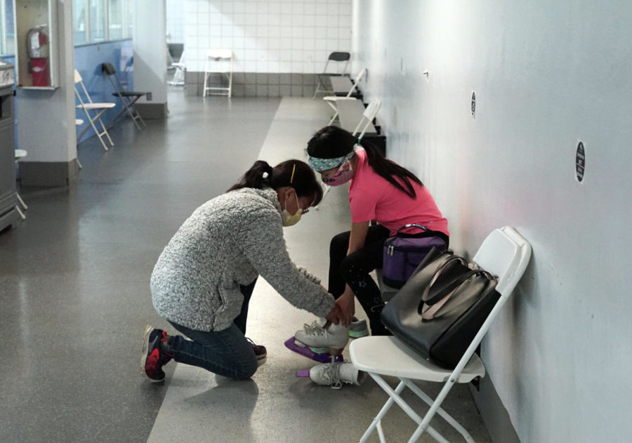 Chen's mother Helen Wang ties her skates before she goes into the ice.