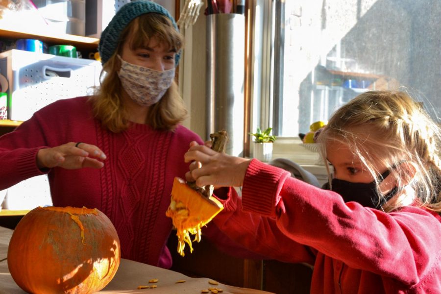 Senior Alice Duncan carves a pumpkin with a kindergartener at the annual Senior Kindergartener Halloween pumpkin carving activity.