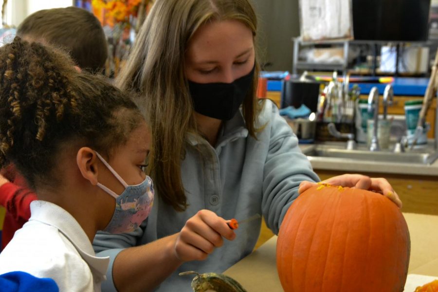 Senior Elizabeth Trevathan carves a pumpkin with a kindergartener.
