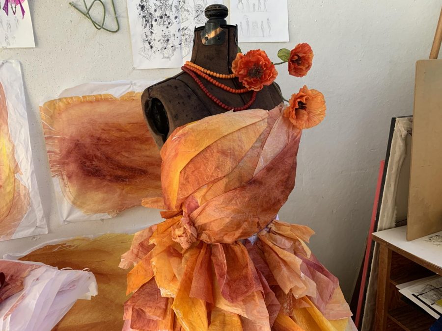 Besse is using handmade sheets of colorful tissue paper taped and folded together to build the dress.