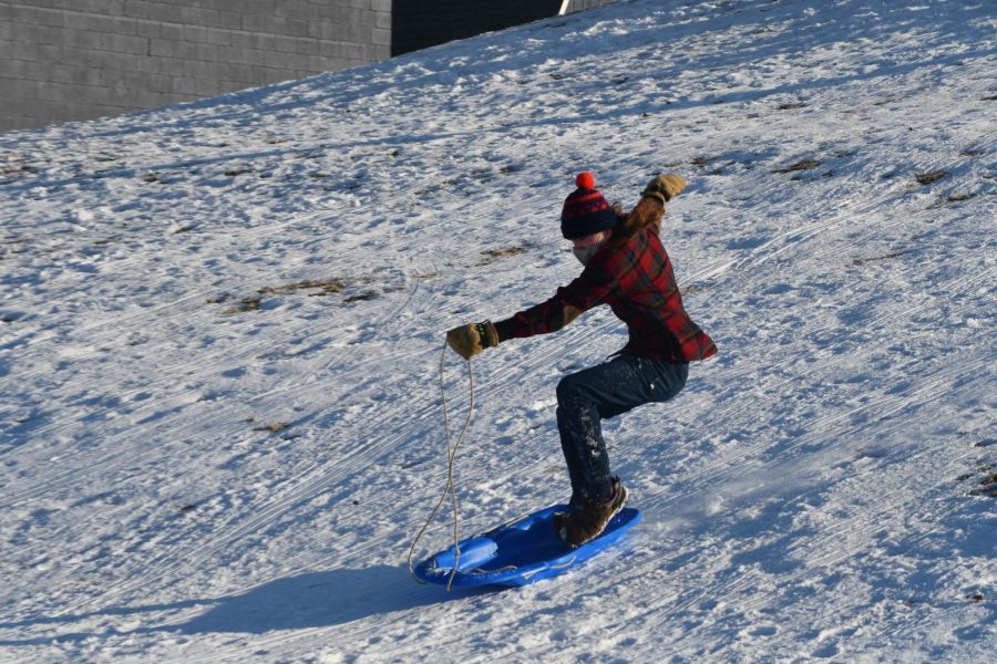 SURFING THE SNOW. Senior Will Sedo balances on a sled as he goes down the hill. Sedo said, It was really great to get out sledding with Outdoors Club on Thursday. We’ve had sledding parties like this in past years, but this was by far the biggest crowd we’ve ever had. It was fantastic to see everybody out there, and the hot chocolate was a treat.