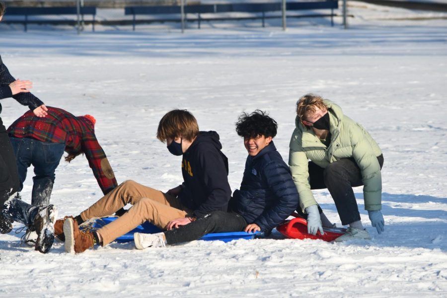 TEAMWORK, DREAM WORK. Seniors Annika Brelsford, Pah Na, Grant Mortenson, Will Sedo and more, hop on Na's large blue sled together as they speed down the hill. Na said, "I brought my own sled which was nice and we were able to get five people on the sled at once going down the hill. I was on top of Grant’s shoulders. I thought it was really fun, it was great to see everyone out there wiping out or chilling with their hot chocolate."