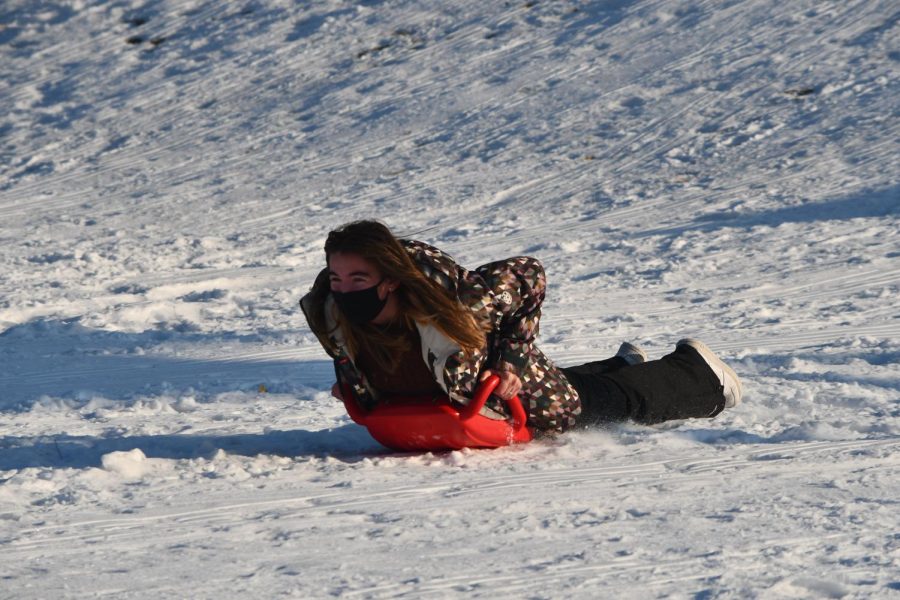 ALL SMILES. Co-president Sarah Oppenheim slides down the hill. She said, "We [Outdoors Club] planned it [sledding] very last minute just because we all wanted to go sledding. After talking to the dean we had a way to get hot chocolate which was a key component and then we just had to get the word out. We really expected only like 5 or 6 of our friends to be there so the turnout was shocking. It ended up being a great time and even Principle Collins tried it out."
