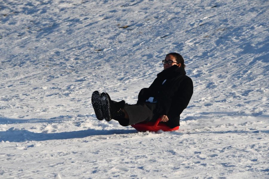 READY SET, SLED. Upper School Principal Theresa Collins joins the fun as she rides down the hill in her warm winter attire.