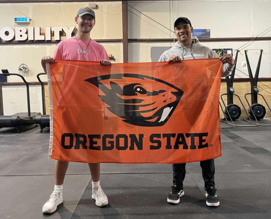 Senior Griffin Ziemer stands with his personal coach, holding a flag of Oregon State University. Ziemer is committed to row there in the fall of next year.