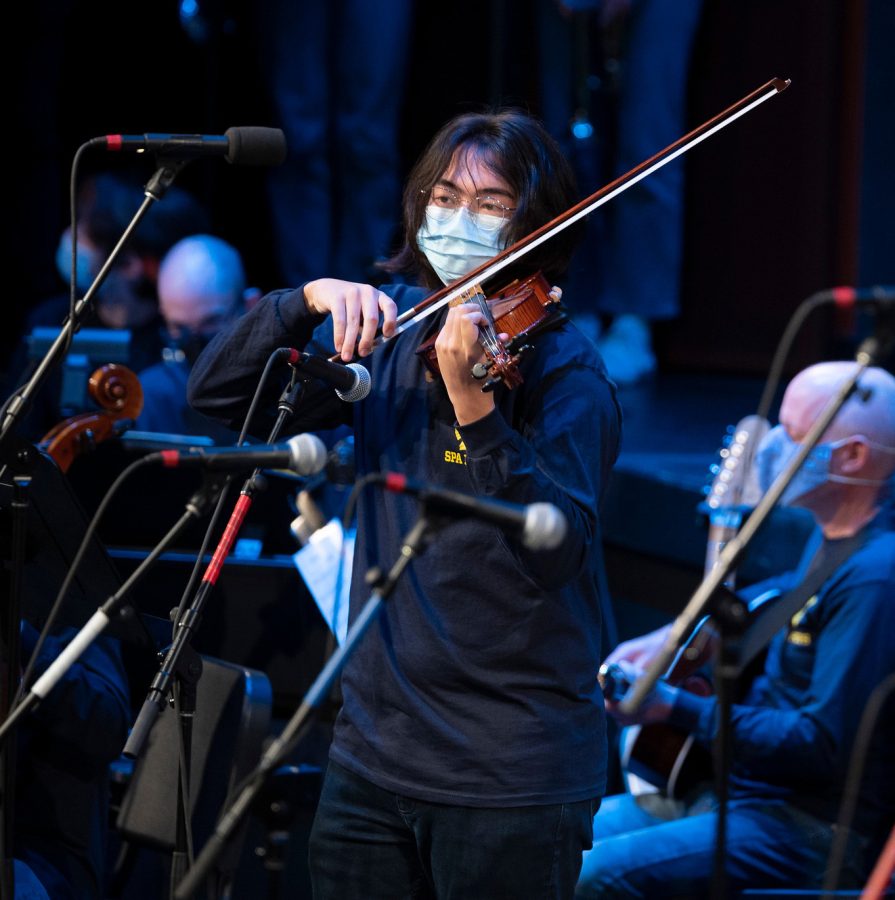 TRING SENSATIONS. Senior Kai Sih accompanies the Academy Chorale during the Pops Concert (right). Sih has played violin for the school orchestra since middle school (left), and their dedication to the instrument is clear through their participation in orchestra programs outside of school as well.