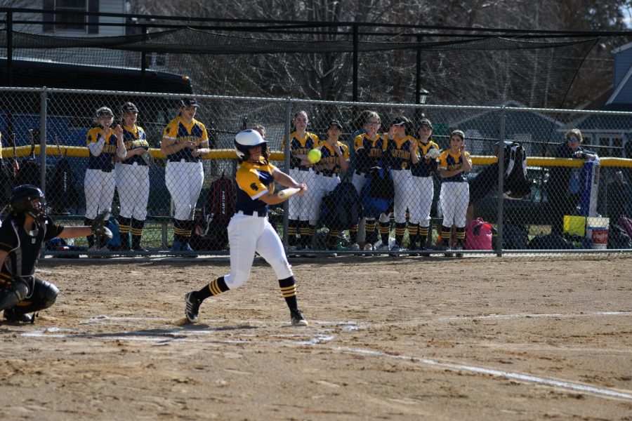 SWING BATTER. Captain Rowan Benz swings at a pitch with her team watching from the dugout. Benz is known most for her pitching, and captain Greta Magnuson said, Benz will "add a new level to the game.”