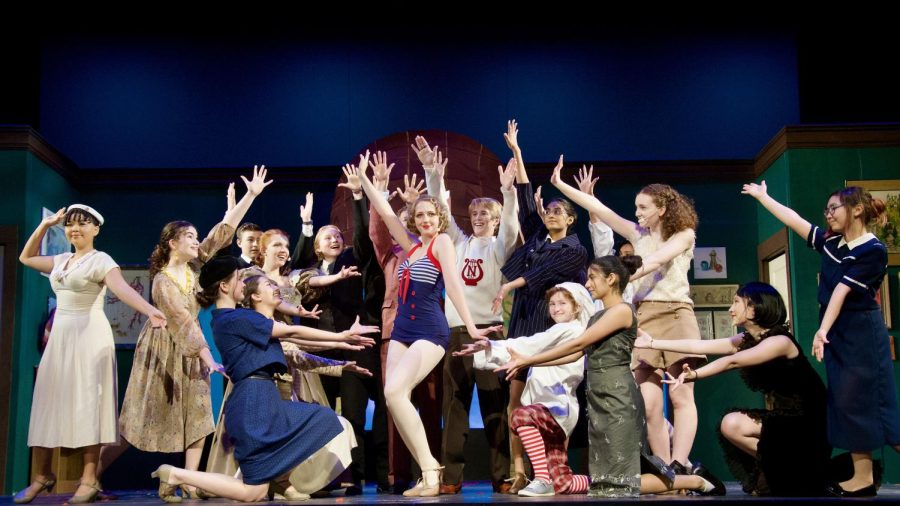 The cast surrounds Annika Brelsford during a musical number.