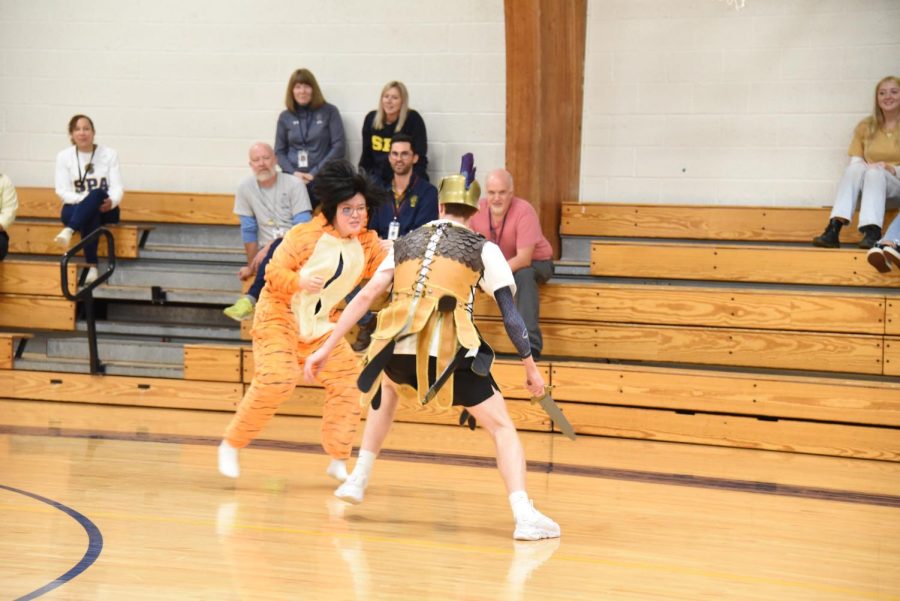 SPARTAN VS. TIGER. Senior Spartan Tommy Verhey chases junior Oliver Zhu (dressed as a tiger) across the gym. Verhey eventually slayed the tiger to fire up the audience for the Boys Soccer teams Homecoming matchup against the Minneapolis South tigers.
