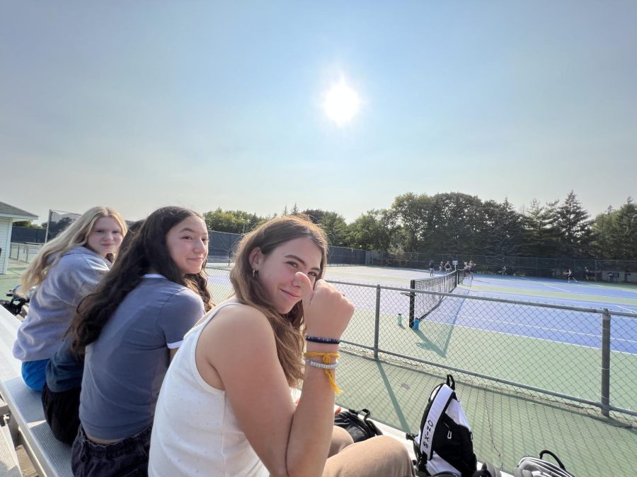 THUMBS UP. Soccer players Clare Ryan-Bradley Sonia Kharbanda, and Evy Sachs sit on the bench, waiting for the tennis match to start.