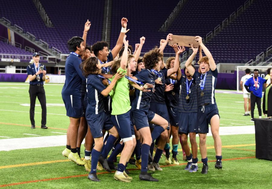 WE ARE THE (STATE) CHAMPIONS. The team celebrates their accomplishment after captains Nathan Cohen, Cooper Bollinger Danielson and Yash Kshirsagar present the plaque to the group.