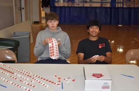 HELPFUL HAND. Seniors Maverick Wolff and Rio Cox help students submit their ballots. The pair was also handing out "I Voted" stickers, and instructed mock voters what to do.