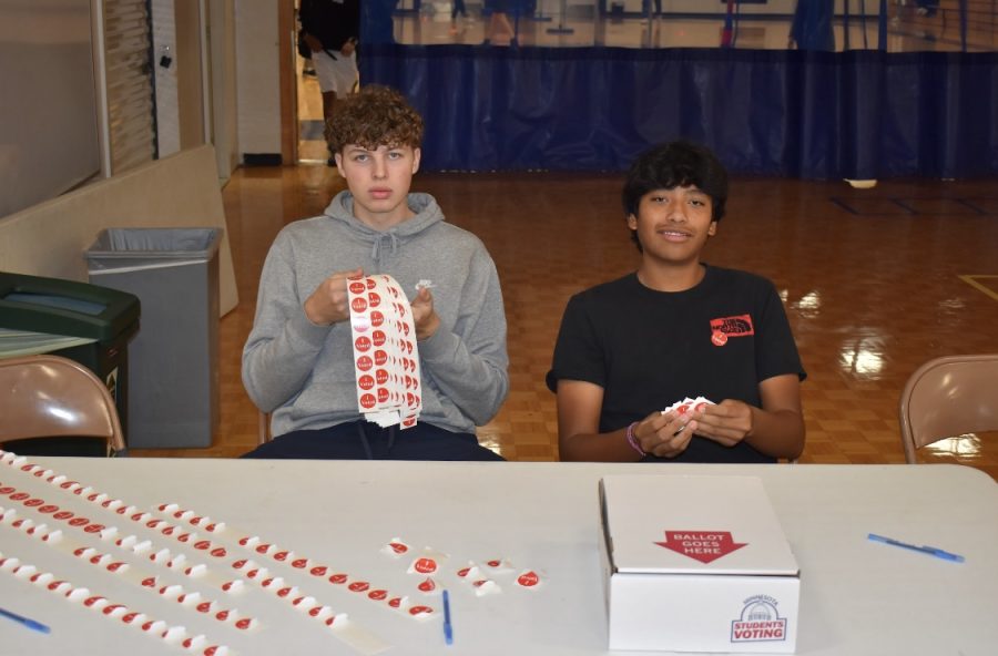 HELPFUL HAND. Seniors Maverick Wolff and Rio Cox help students submit their ballots. The pair was also handing out I Voted stickers, and instructed mock voters what to do.
