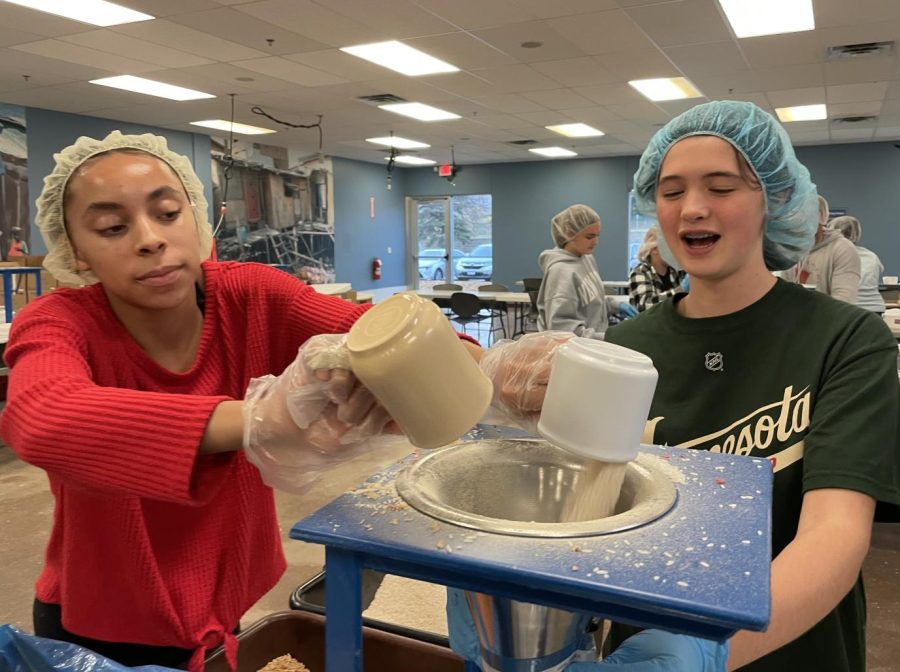 HAVE A CUP. Julia Taylor and Adele Gjerde measure the right amount of protein powder and rice and pour it through a funnel into the bag that will be sealed as a serving.