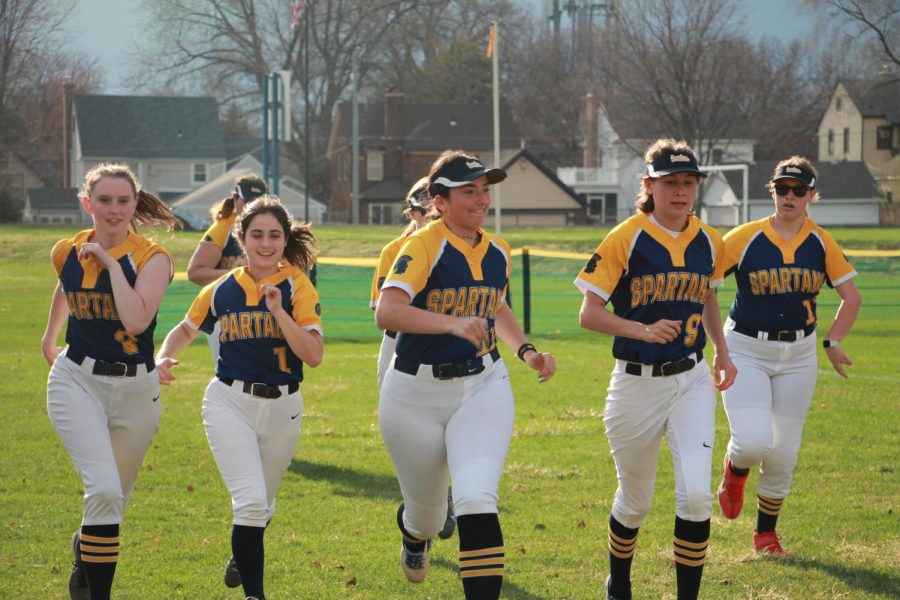 STAYING WARM Spartans Softball team jogs to the fence and back between innings in their game against Breck Apr. 14. This was the teams second game of the season putting them at a record of 2-1-0  Junior Poppy Ploen says “Im really looking forward to seeing how our team performs because we are significantly stronger than we have been in some of our past years”
