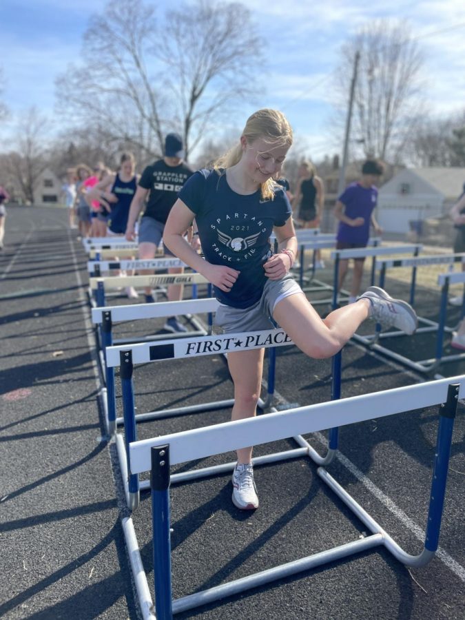 FIRST PLACE. Freshman Maren Overgaard leaps over hurdles with nothing but enthusiasm. She proceeded to practicing for her long-distance events and pushed through for the remaining 30 or so minutes. We were doing hurdle mobility drills before our workout. It’s a fun warmup that’s a little different from our traditional warmup, says Overgaard.
