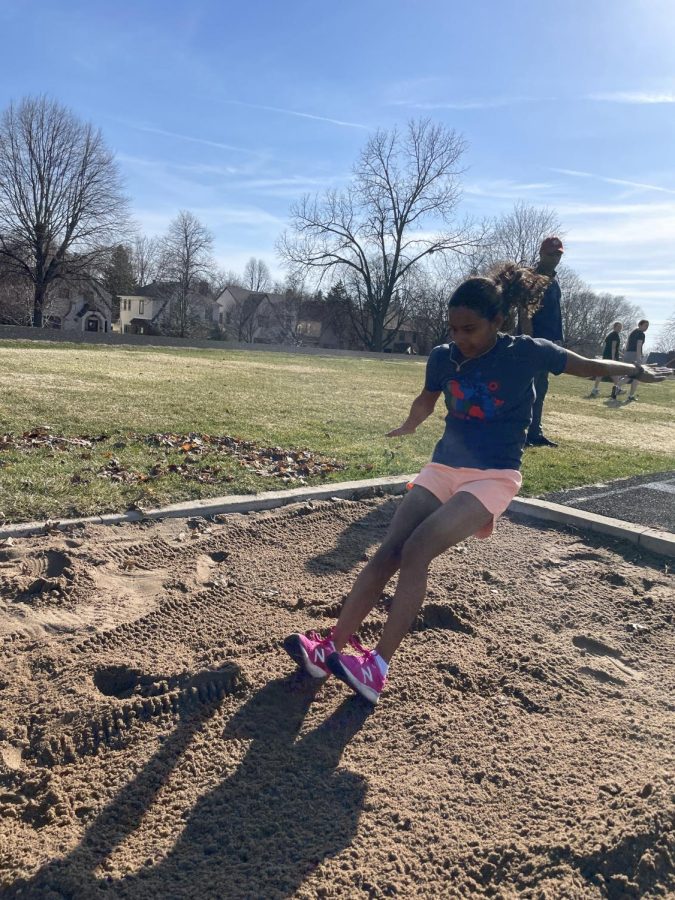 SANDSTORM. Junior Nora Shaughnessy leaps over the long jump pit with her arms acting like wings, propelling her forwards. Before practice, she had never done long jump, high jump being her area of expertise. “I wanted to try something new, such as long jump instead of high jump, during practice,” exclaimed Shaughnessy.