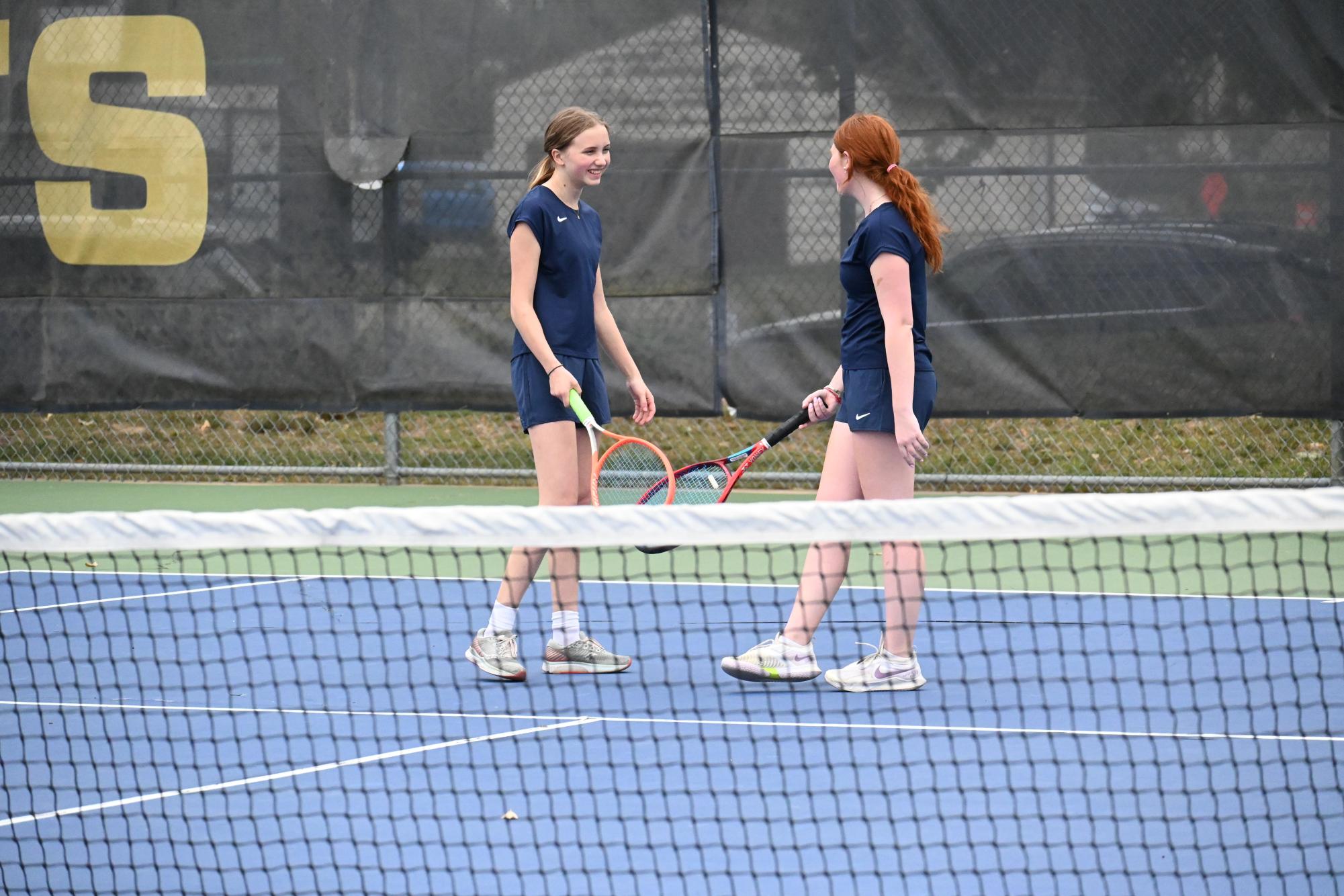 RACKET FIVE. Junior Liza Thomas and Senior Lucy Shaffer bump rackets to congratulate each other after scoring a point.  