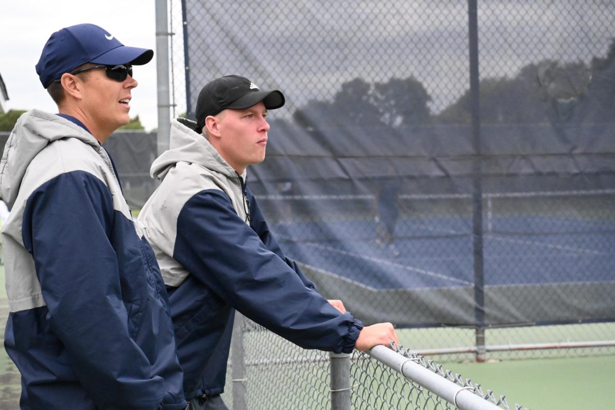 OBSERVING THE MATCH. Coach Jono Martin and Jacob Smith stand by the court while discussing how the match is progressing. 