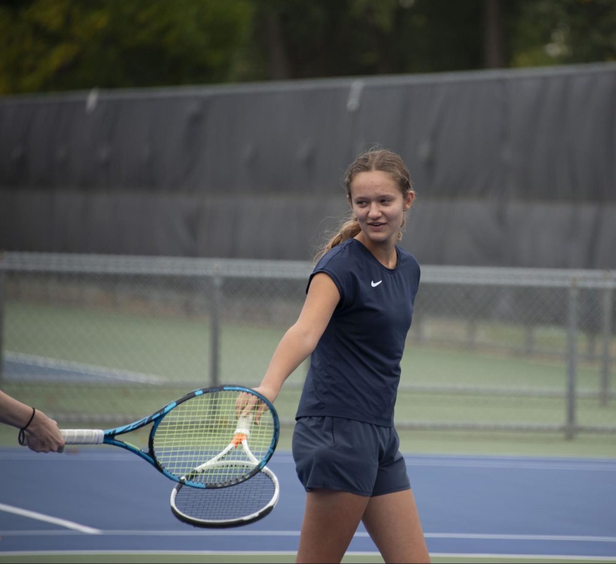 PARTNERS. Sophomore Elle Williams taps rackets with her doubles partner after a good point. Despite her strong desire to, Williams has never had the opportunity to play competitive doubles with her brother, Aidan Williams. “We’ve never competed in a tournament together because tournaments rarely offer mixed doubles,” she said.