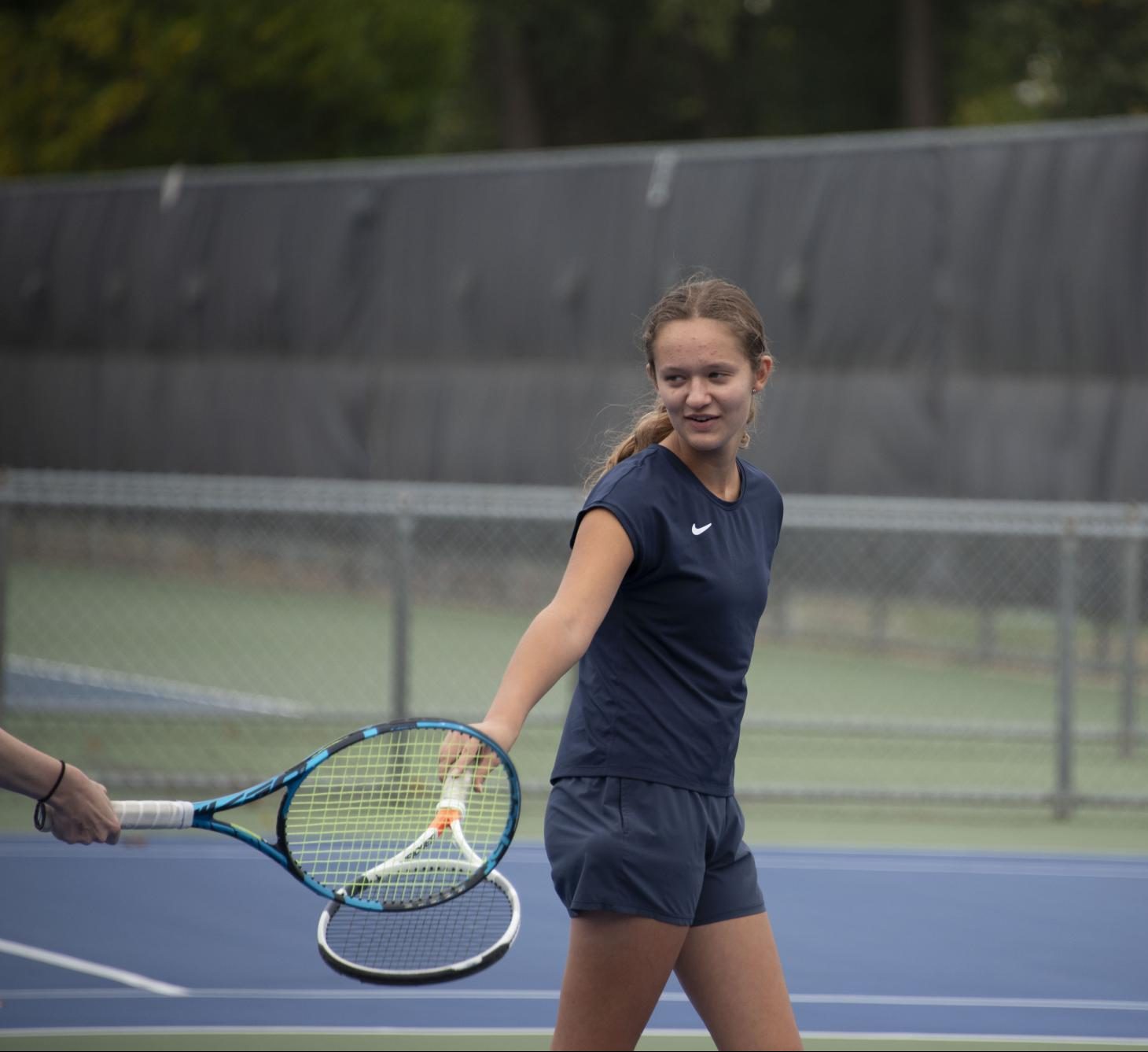 PARTNERS. Sophomore Elle Williams taps rackets with her doubles partner after a good point. Despite her strong desire to, Williams has never had the opportunity to play competitive doubles with her brother, Aidan Williams. “We’ve never competed in a tournament together because tournaments rarely offer mixed doubles,” she said.