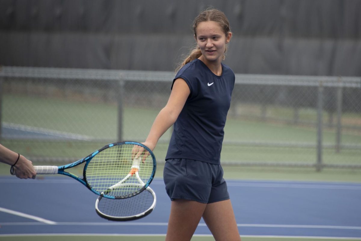 PARTNERS. Sophomore Elle Williams taps rackets with her doubles partner after a good point. Despite her strong desire to, Williams has never had the opportunity to play competitive doubles with her brother, Aidan Williams. “We’ve never competed in a tournament together because tournaments rarely offer mixed doubles,” she said.