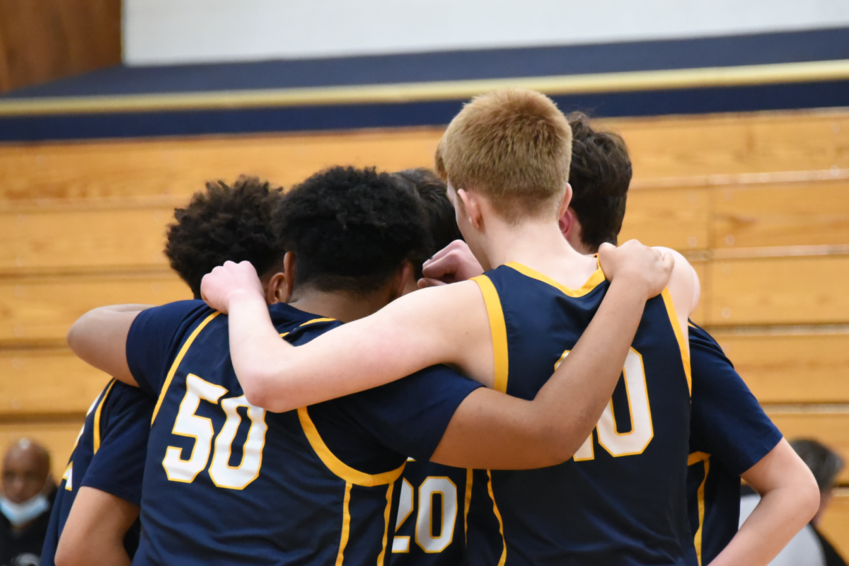 TEAM. Boys basketball athletes huddle up in a circle, supoprting one another during a game. This support is one of the many positives the athletics programs foster. Athletes and families largely reported that SPA athletics live up to the school mission, Senior Siri Pattison said.