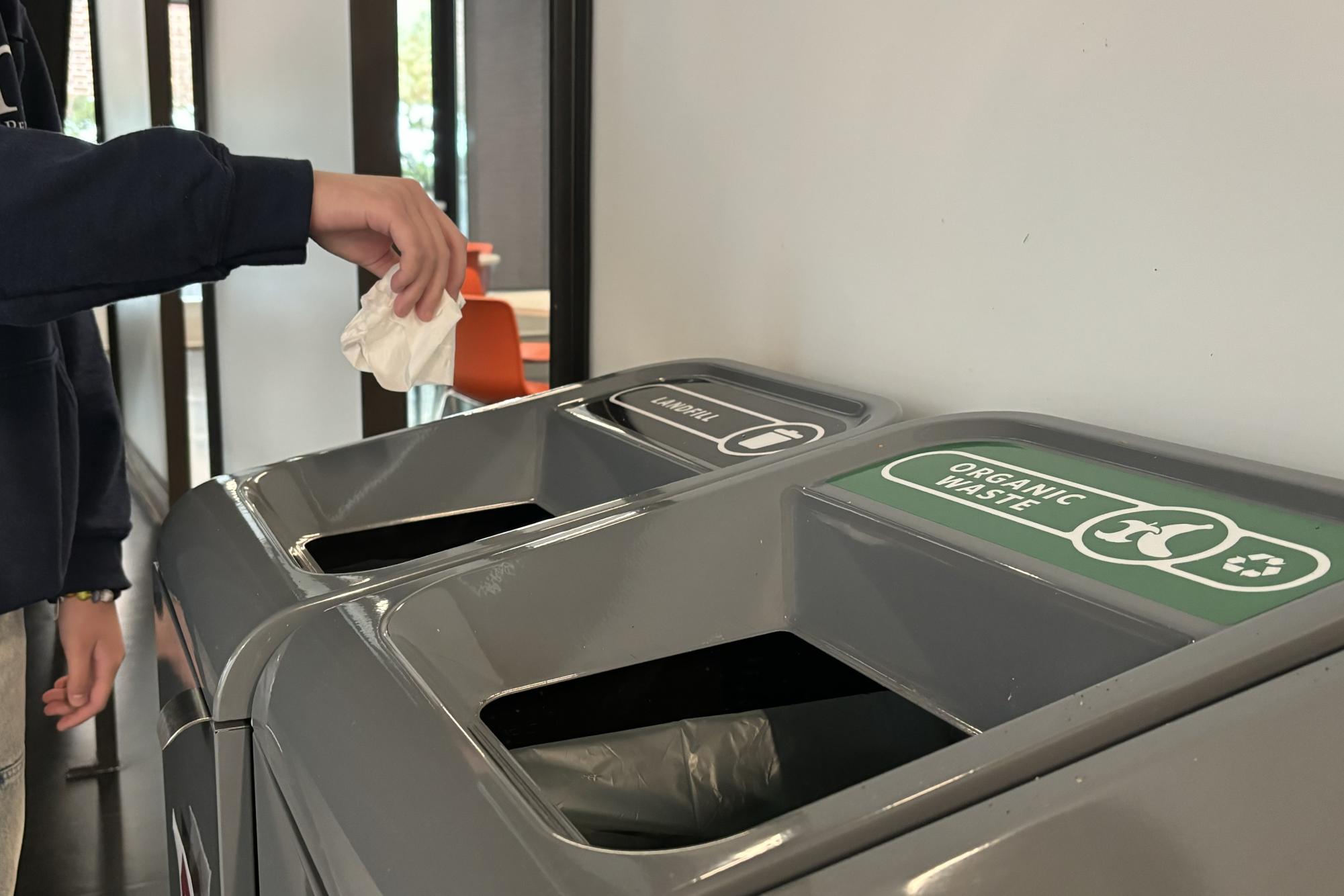WHERE DOES THIS GO. After using a tissue to clean up some spilt water, sophomore Carys Hsiung wonders which bin to to throw it in before dropping it into the one that says landfill.