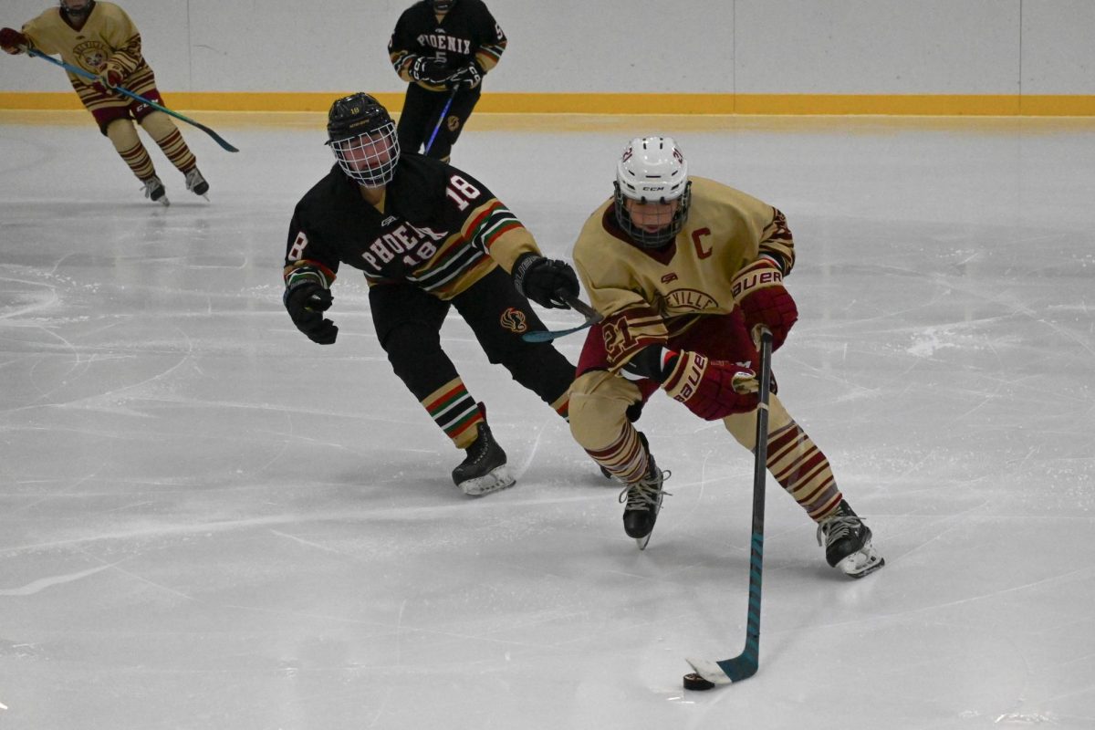 TAILING CLOSE BEHIND. Phoenix No. 18, Ella Berthiaume from St. Agnes, quickly chases after Cougar player No. 21 while she is in possession of the puck. Teammates from each team were rushing over to assist their players, but the two chasing after the puck sped right past them.
