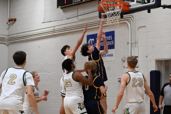 LEAP AND PRAY. Rawdon leaps into the air and launches the ball toward the hoop, surrounded by Wildcats looking to block the ball.