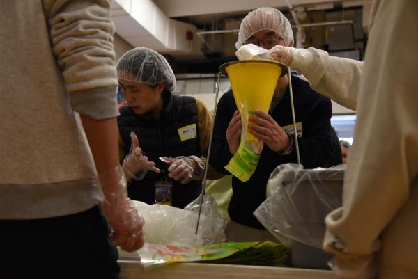 HEADS DOWN, HANDS ON. Each packaged meal requires three scoops of oatmeal, sugar, and cinnamon in rotating order. Each table is busy with their hands and minds. 