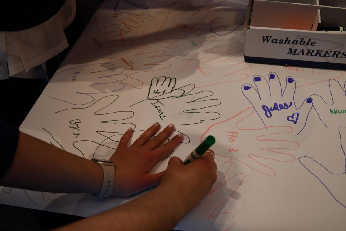 LEAVE A MARK. Students trace the outlines of their hands on a poster after the march. The poster will be a permanent reminder of the changes made to the SPA policy.