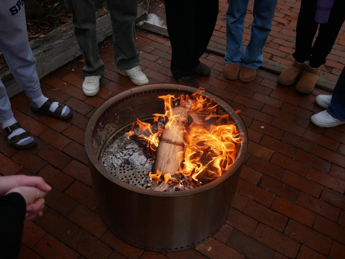 ROARING. The fire thrives while being tended to by students. Senior Emme Krienke kept the fire going. I actually learned my skills at my semester away at Chewonki. I learned a lot about how to orient the wood to get the flame to catch, Krienke said. 