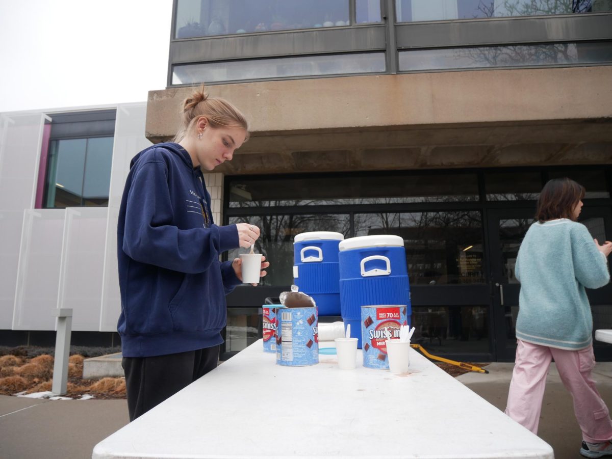 COMMUNITY COCOA. Junior Natalie Waibel stirs her hot chocolate. Along with smores supplies, hot cocoa was available for students. 