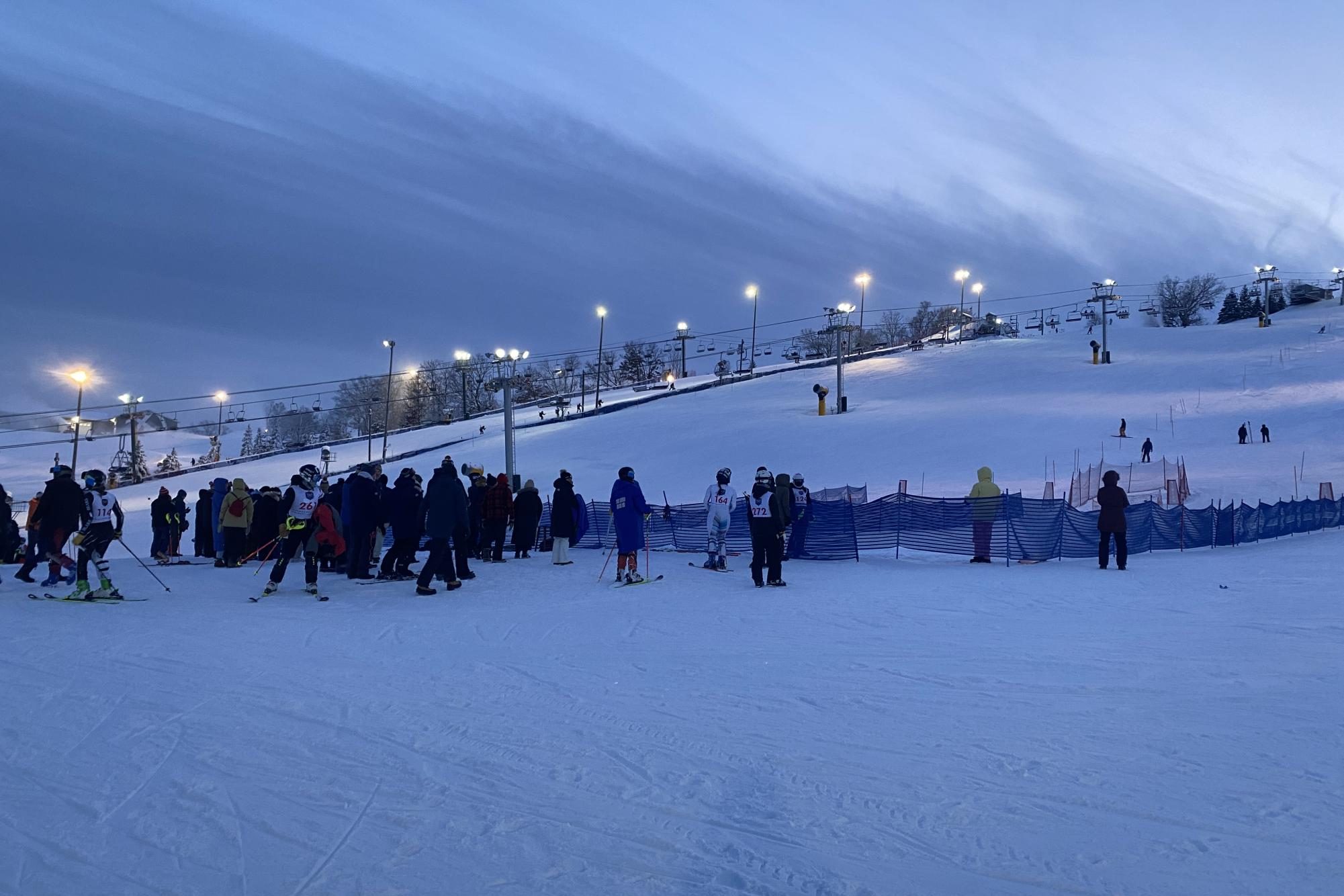 CHILLY AFTERNOON. The sky begins to darken as alpine racers fly down the hill and spectators watch intently from the bottom.