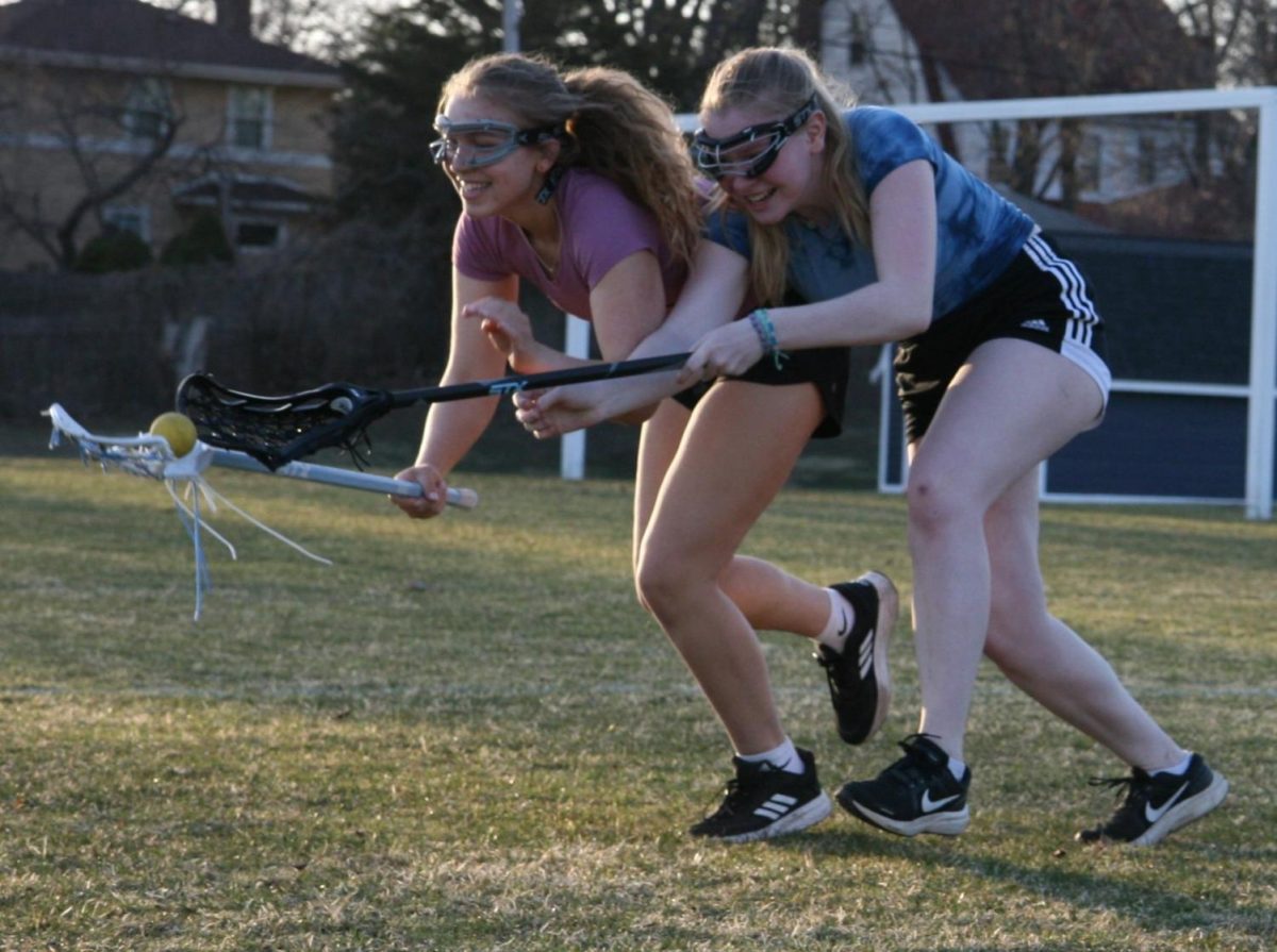 STEALING THE BALL. Evy Sachs attempts to take the ball from Nora McKoy during a lacrosse practice. During a defense drill, the team was practicing getting up close to the other players. Run Nora Run, one of their teammates shouted.