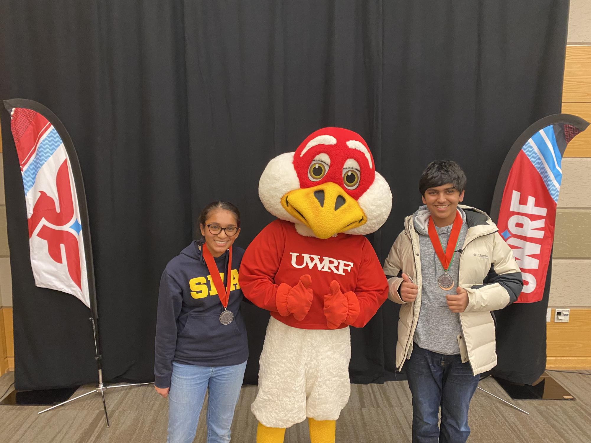 SILVER MEDALISTS. Sophomore Zain Kizilbash and freshman Nabeeha Qadri pose with the University of Wisconsin River Falls mascot after placing second in the Fossils event. (Submitted Photo: Nabeeha Qadri)