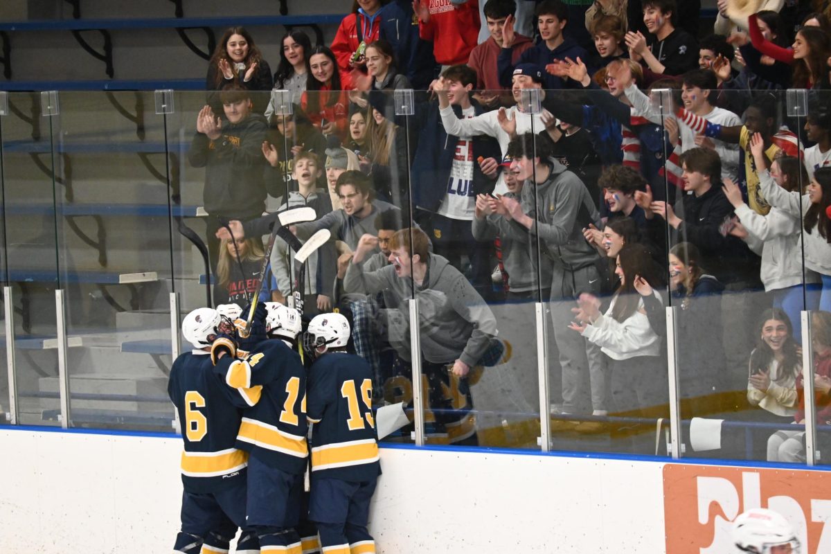 CHEER SQUAD. The Spartans huddle up, celebrating a point, as classmates cheer on by the side.
