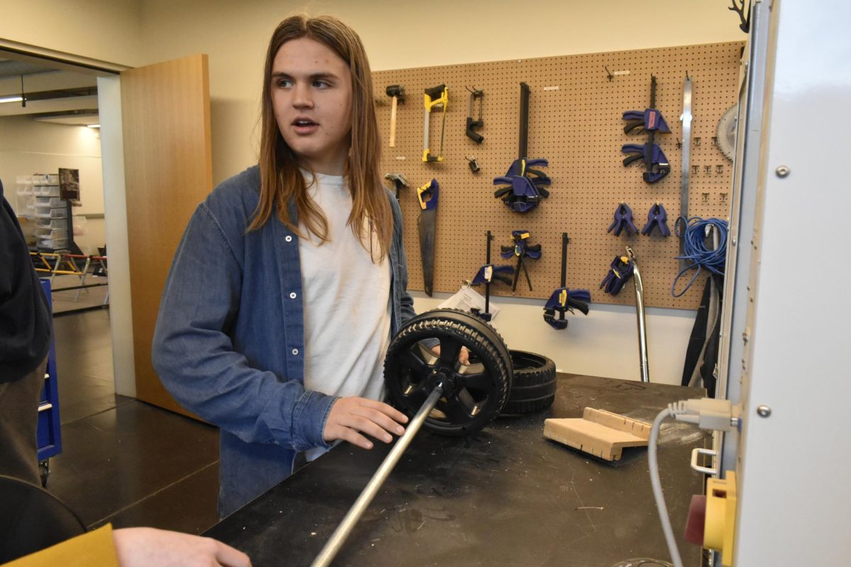WHEELS TURNING. Freshman Leif Rush discusses about the wheels for the go-kart as he stands in the workshop. 